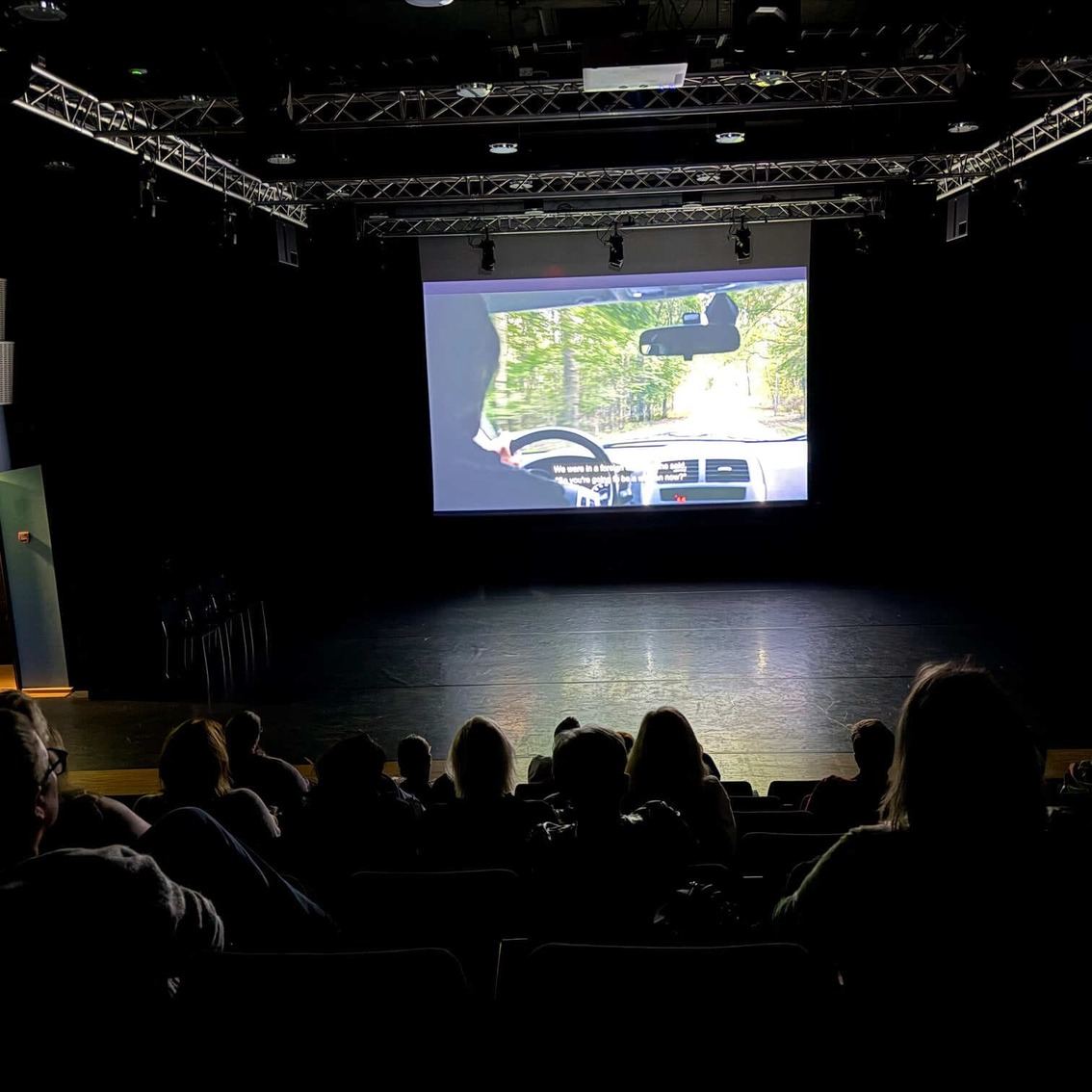 Publik sitter i en mörk salong och tittar på en film som projiceras på en stor duk.