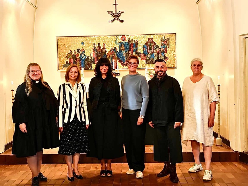 Sex personer står tillsammans framför altaret i en kyrka under invigningen av en ikonutställning.