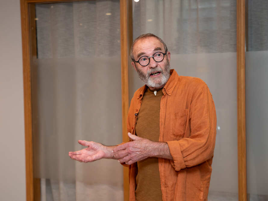 En man talar och gestikulerar inför en mindre grupp inomhus.